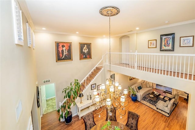 living area with an inviting chandelier, crown molding, a high ceiling, and wood finished floors