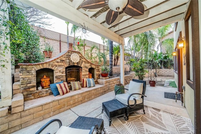 view of patio / terrace featuring a fenced backyard, ceiling fan, and an outdoor living space with a fireplace