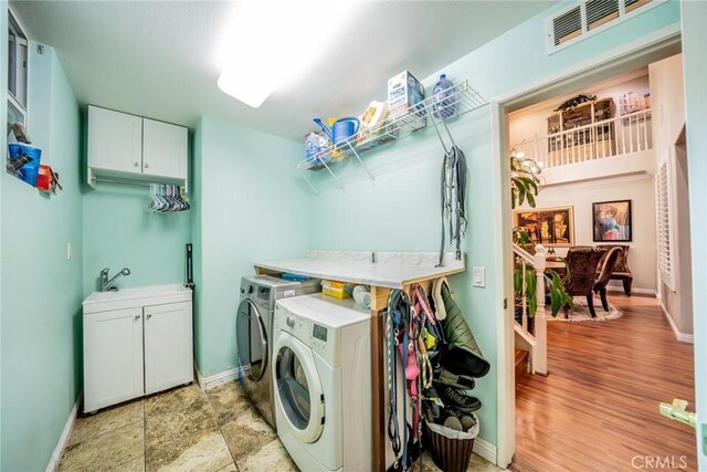 laundry room featuring cabinet space, baseboards, visible vents, washing machine and clothes dryer, and a sink