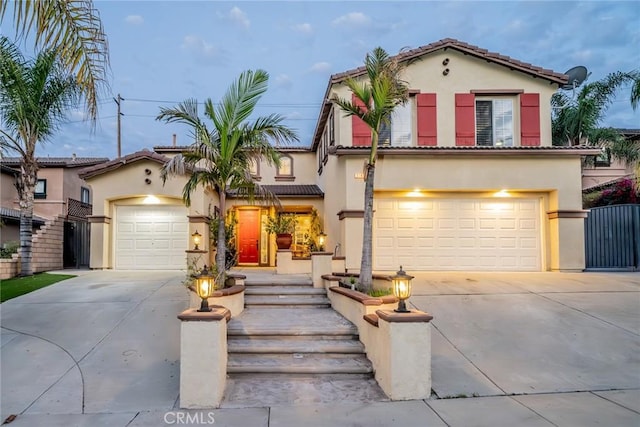 mediterranean / spanish home with driveway, a tile roof, a garage, and stucco siding