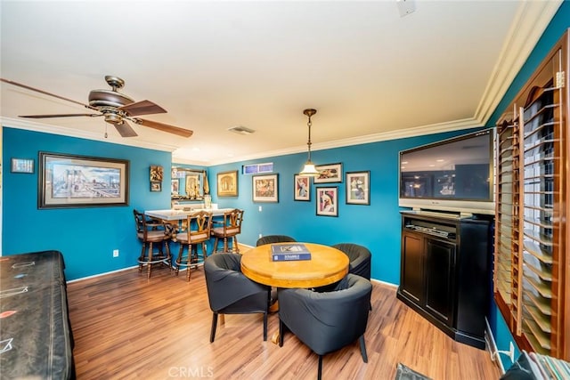 dining space featuring baseboards, crown molding, and light wood finished floors