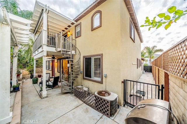 back of house featuring a patio area, fence, stairway, and stucco siding