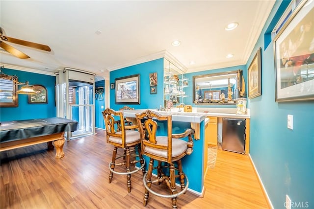 bar with ornamental molding, stainless steel dishwasher, light wood-style flooring, and baseboards