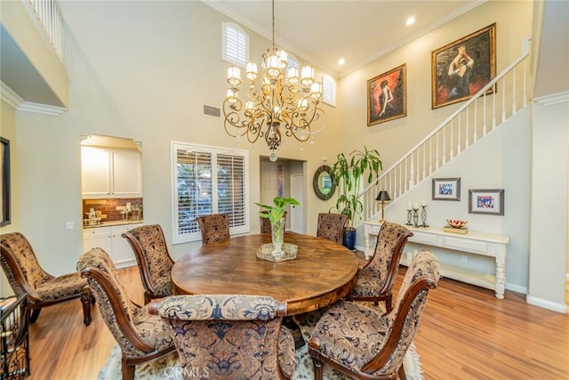 dining room with light wood-style flooring, stairway, a chandelier, and crown molding