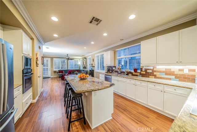 kitchen featuring appliances with stainless steel finishes, a kitchen island, a sink, and crown molding