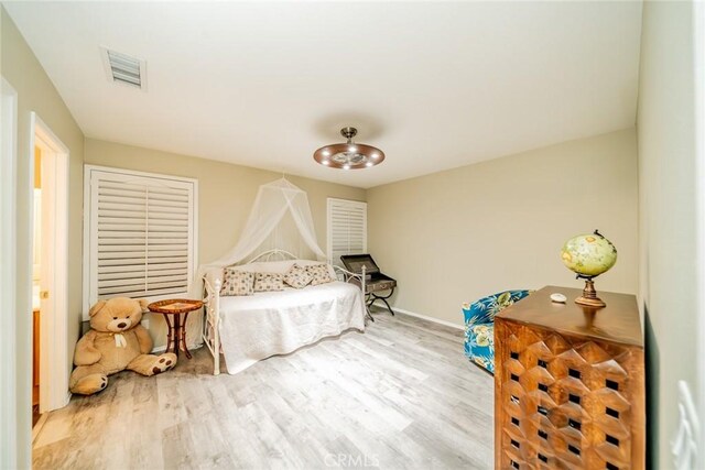 bedroom featuring wood finished floors, visible vents, and baseboards