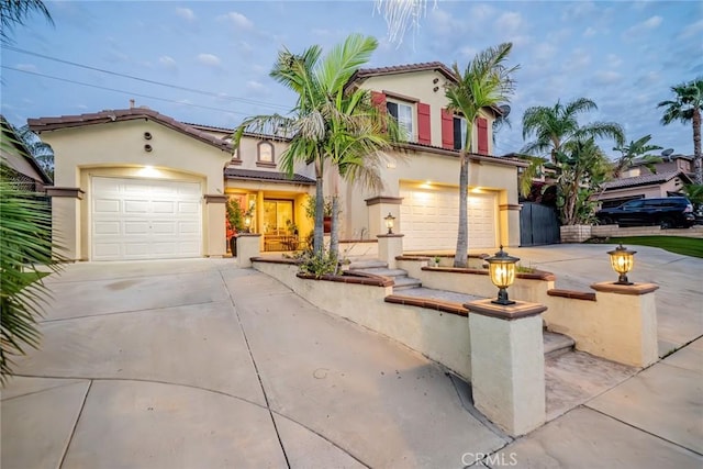 mediterranean / spanish home featuring concrete driveway, a tiled roof, and stucco siding