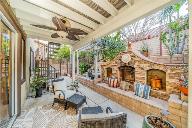 view of patio with stairway, fence, an outdoor stone fireplace, and a ceiling fan