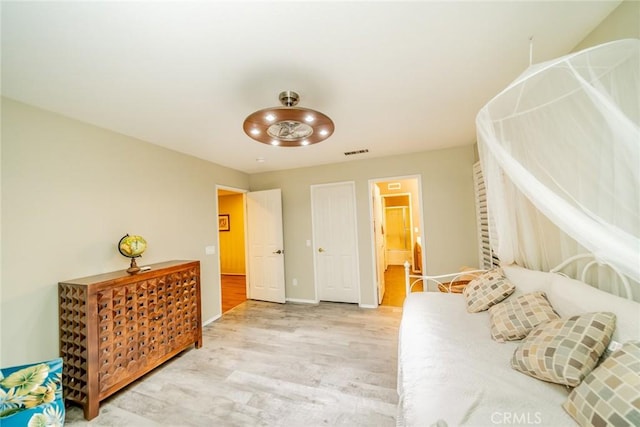 bedroom with baseboards, visible vents, and wood finished floors