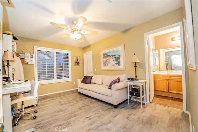 office space featuring ceiling fan, a sink, light wood-style flooring, and baseboards