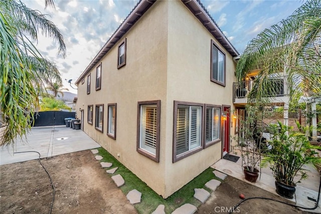 view of side of home featuring a patio area, fence, and stucco siding