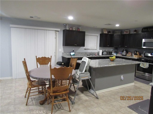 kitchen featuring dark cabinetry, a center island, visible vents, and stainless steel appliances