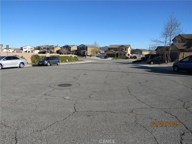 view of road featuring street lights, sidewalks, curbs, and a residential view