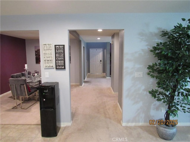 hallway featuring baseboards and light carpet