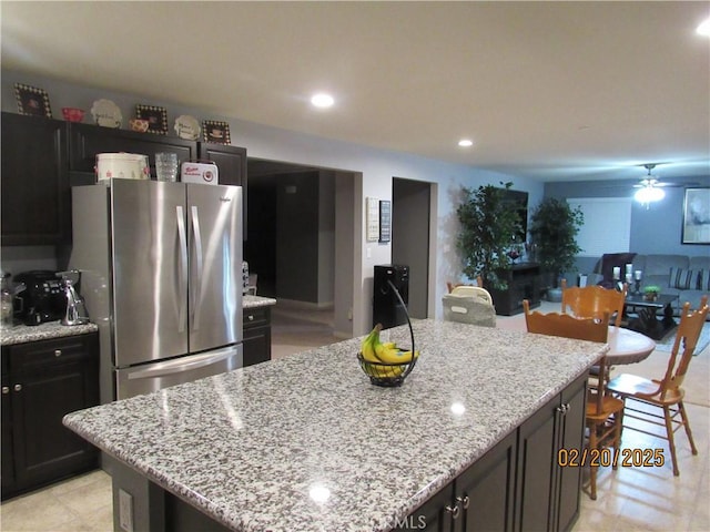 kitchen with recessed lighting, a kitchen island, freestanding refrigerator, and light stone countertops