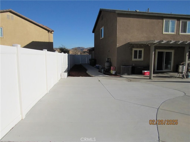 rear view of property featuring stucco siding, central AC, and a patio area