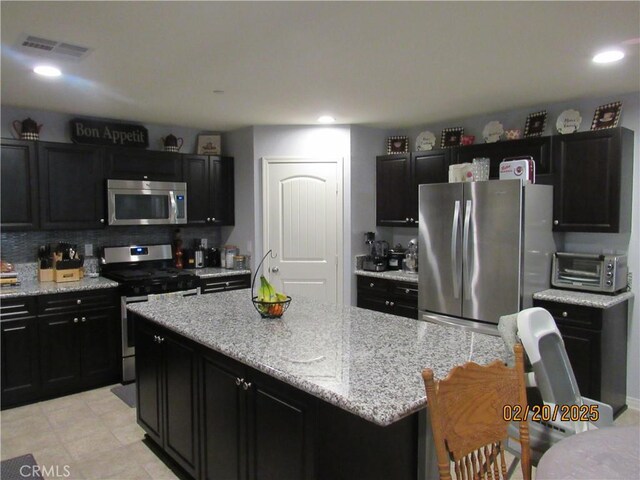 kitchen with visible vents, appliances with stainless steel finishes, dark cabinetry, and a toaster