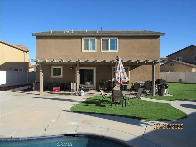 back of property featuring stucco siding, a pergola, a yard, and fence