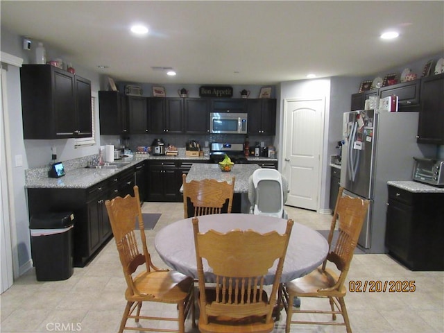 kitchen featuring tasteful backsplash, recessed lighting, appliances with stainless steel finishes, and dark cabinetry