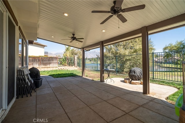 view of patio / terrace featuring a water view, fence, and a ceiling fan