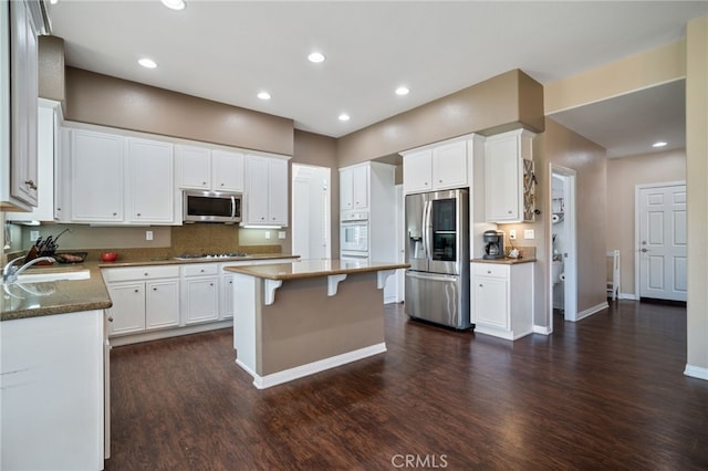 kitchen featuring appliances with stainless steel finishes, white cabinets, dark wood-type flooring, and a sink