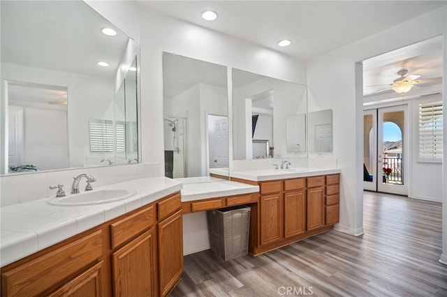 bathroom featuring a ceiling fan, two vanities, a sink, and wood finished floors