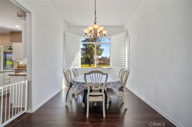 dining area with baseboards, dark wood finished floors, and an inviting chandelier