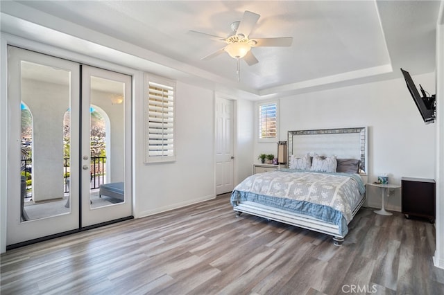 bedroom featuring wood finished floors, baseboards, access to exterior, french doors, and a tray ceiling