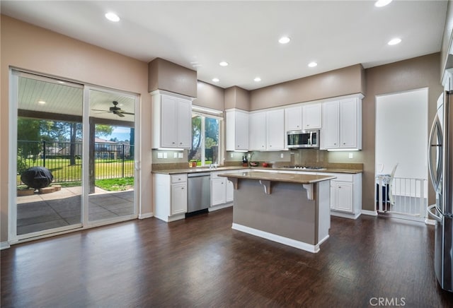 kitchen featuring appliances with stainless steel finishes, dark wood-style flooring, a kitchen bar, and white cabinets