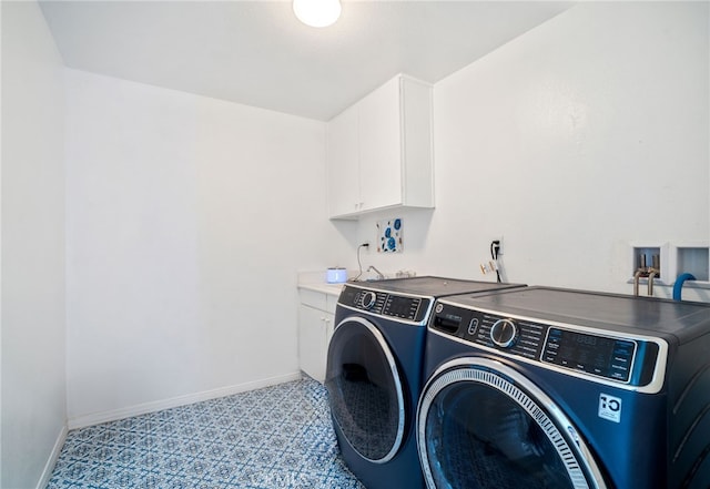 clothes washing area featuring washing machine and dryer, cabinet space, and baseboards