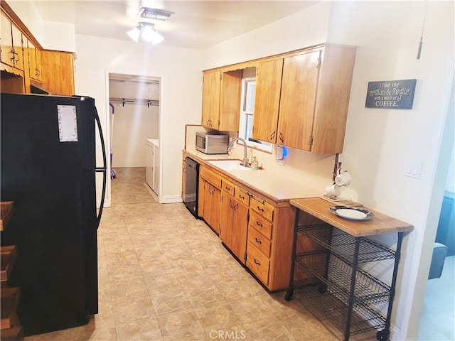 kitchen with a sink, visible vents, light countertops, black appliances, and washing machine and clothes dryer