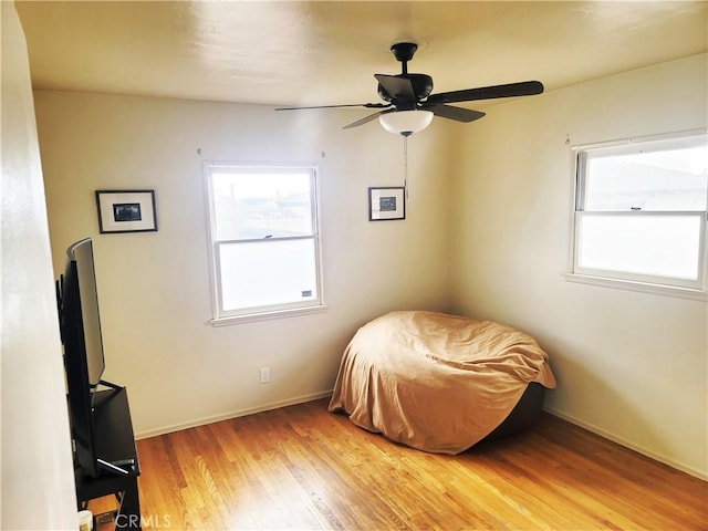 bedroom with light wood-style flooring, baseboards, and ceiling fan