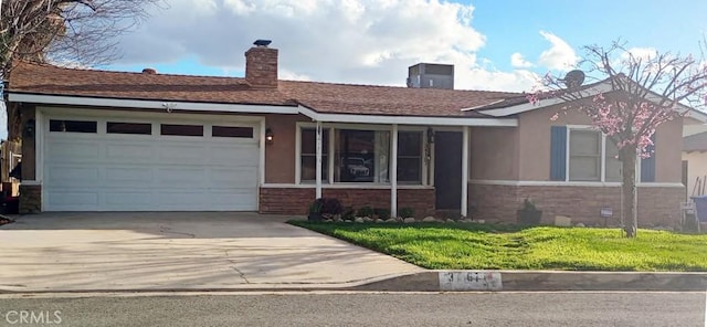 single story home featuring a garage, driveway, a front yard, and stucco siding