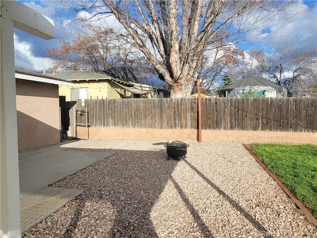 view of yard featuring a fire pit, a patio, and fence