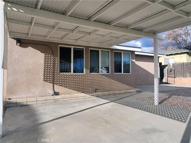 doorway to property featuring fence, a patio, and stucco siding