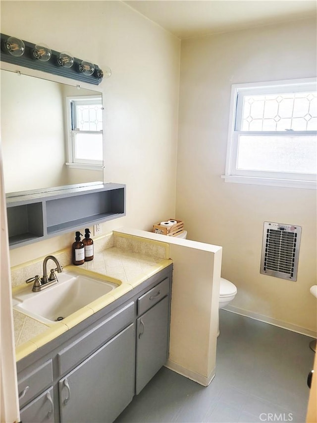 half bathroom featuring vanity, toilet, and heating unit