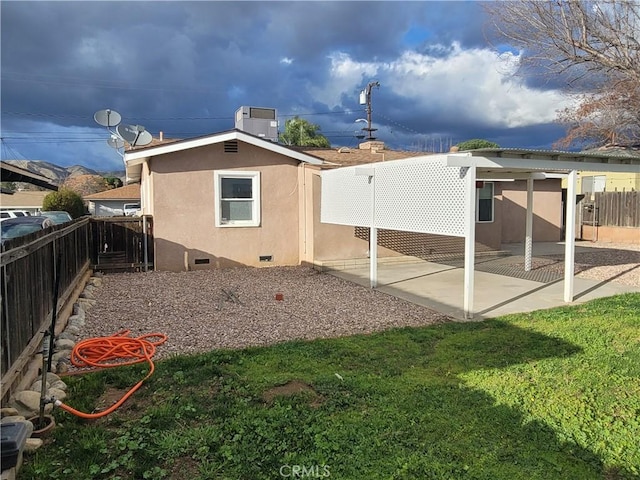 back of house featuring central AC unit, a patio, a fenced backyard, crawl space, and stucco siding