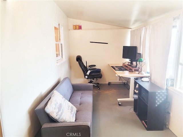 home office with vaulted ceiling and concrete flooring