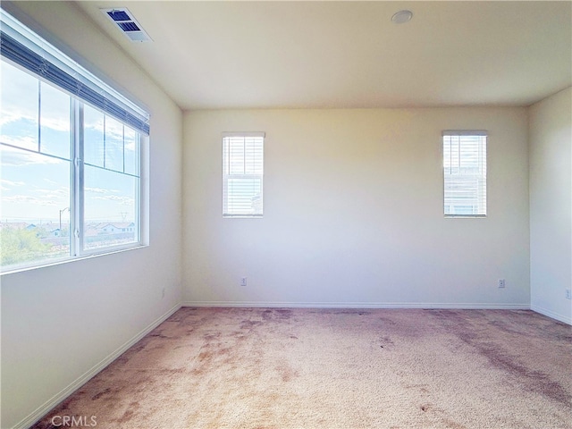 unfurnished room with baseboards, visible vents, and light colored carpet