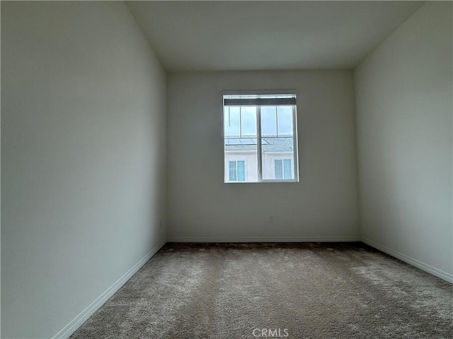 unfurnished room featuring carpet and baseboards