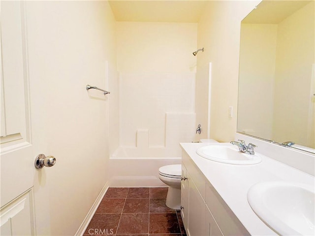 bathroom with toilet, double vanity, baseboards, and a sink