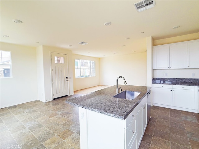 kitchen featuring visible vents, white cabinets, dark stone counters, a sink, and stainless steel dishwasher