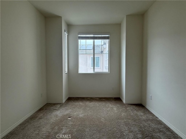 unfurnished room featuring carpet and baseboards