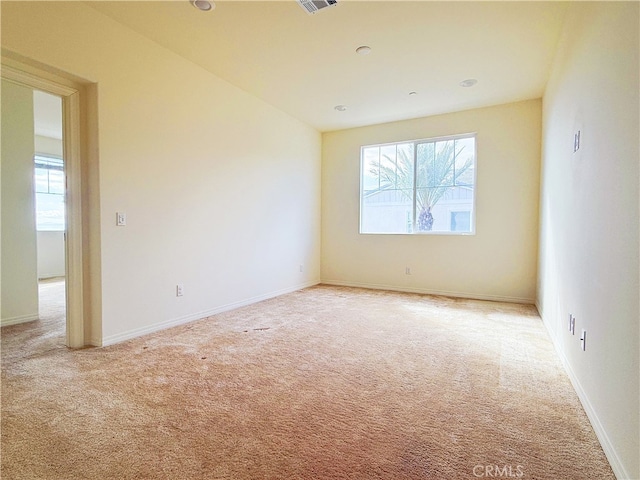 unfurnished room with baseboards, visible vents, and light colored carpet