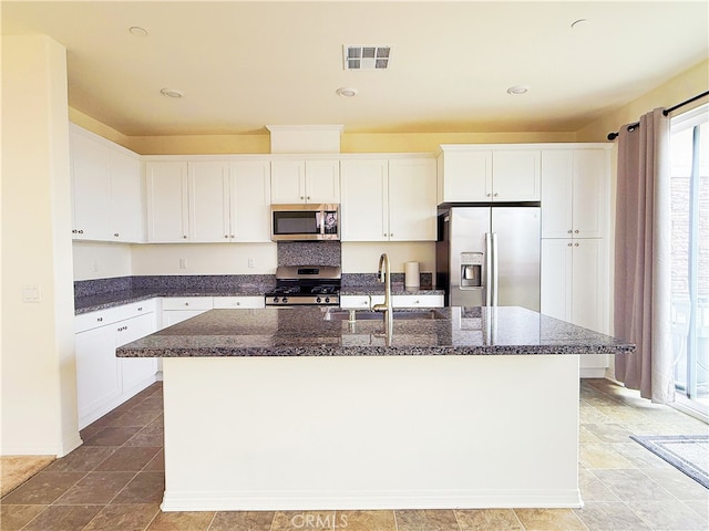 kitchen featuring visible vents, appliances with stainless steel finishes, white cabinetry, a sink, and an island with sink