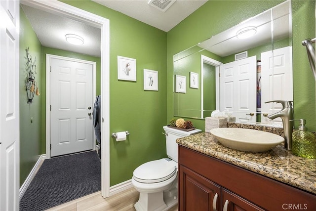 bathroom featuring toilet, vanity, visible vents, and baseboards