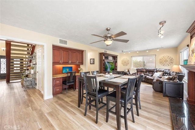 dining area featuring visible vents, ceiling fan, light wood finished floors, and built in study area