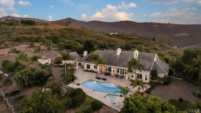 exterior space with a patio area, a mountain view, driveway, and a chimney