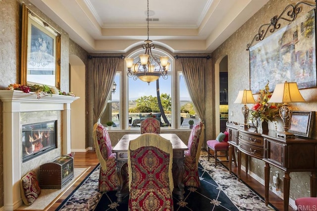 dining room featuring visible vents, an inviting chandelier, a high end fireplace, ornamental molding, and a raised ceiling