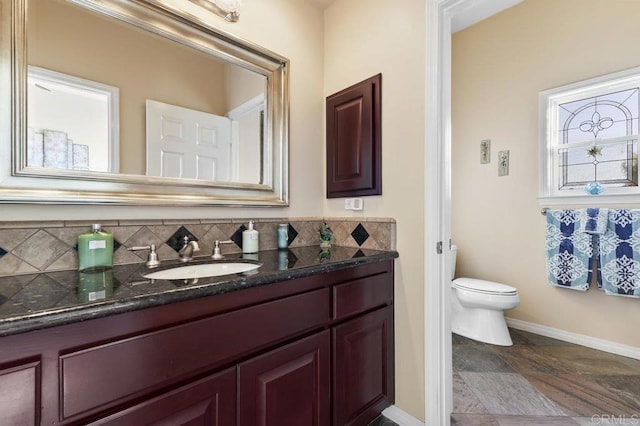 bathroom featuring vanity, toilet, baseboards, and tasteful backsplash